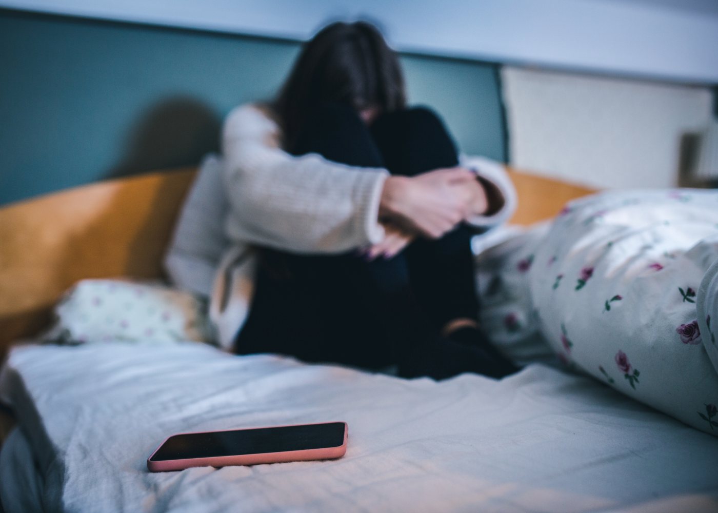 jovem na cama com telemóvel a sofrer de cyberbullying