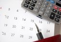 calculadora, caneta e calendário em cima de uma mesa para analisar situação de salários em atraso