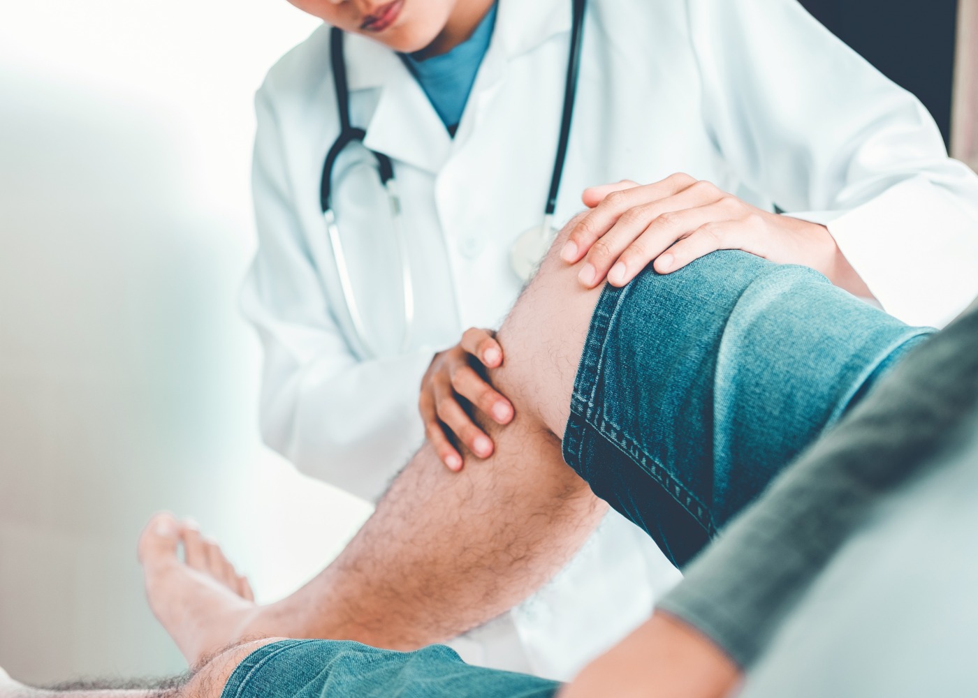 médico a examinar joelho de paciente