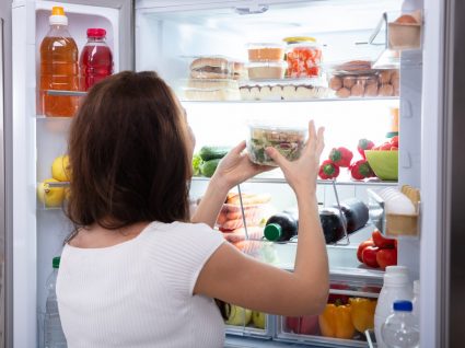 mulher a guardar embalagem no frigorífico