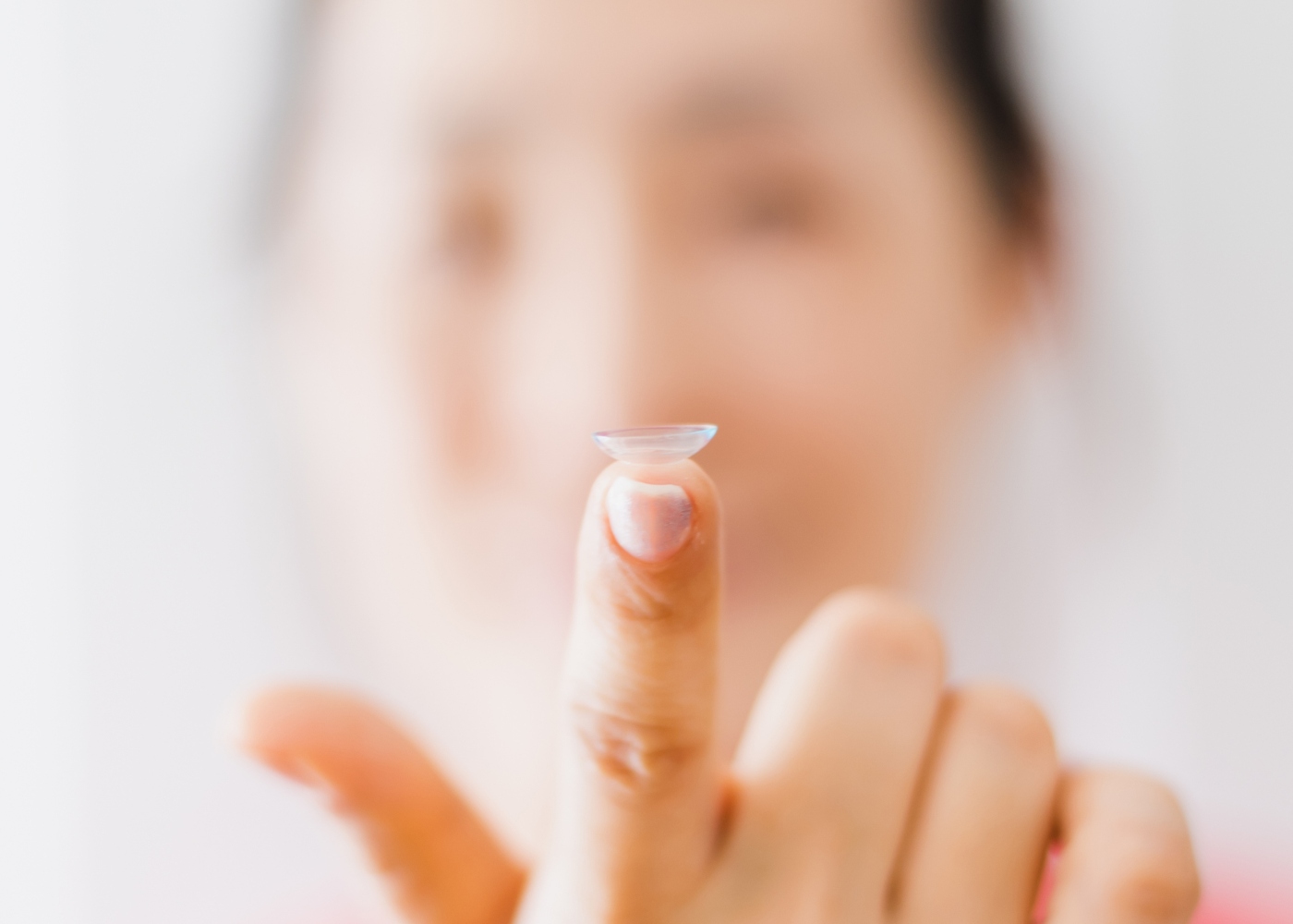 mulher com lente de contacto no dedo