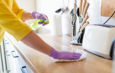 pessoa a limpar o balcão da cozinha e fazer outras tarefas domésticas