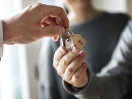 close up nas mãos de uma pessoa a entregar umas chaves de casa a outra