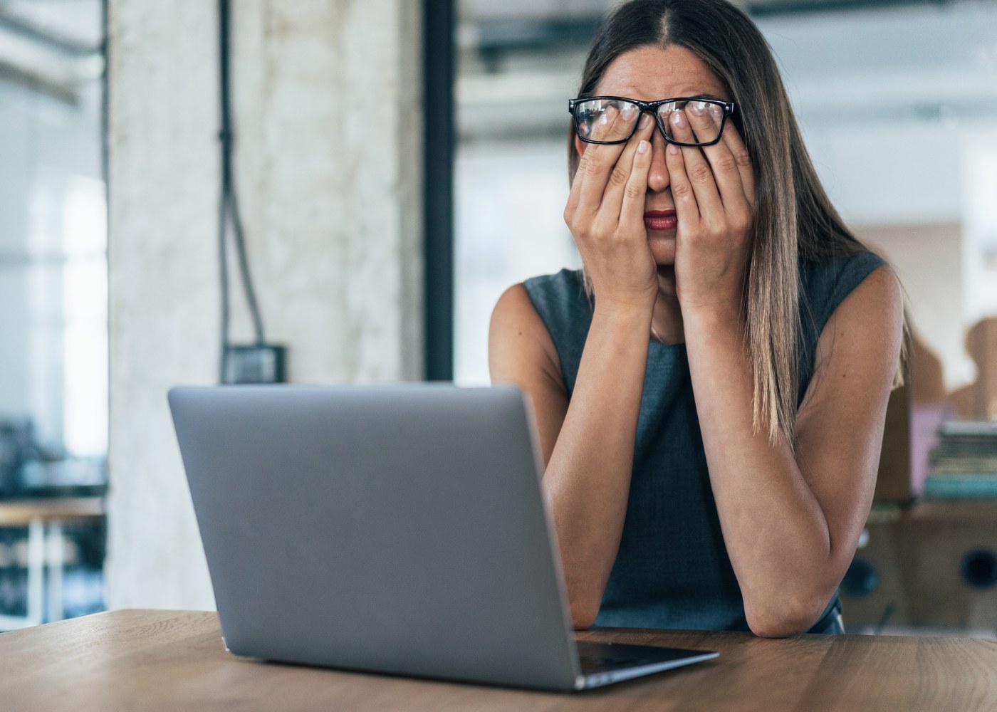 mulher ao computador com ar cansaço a analisar causas de stress no trabalho