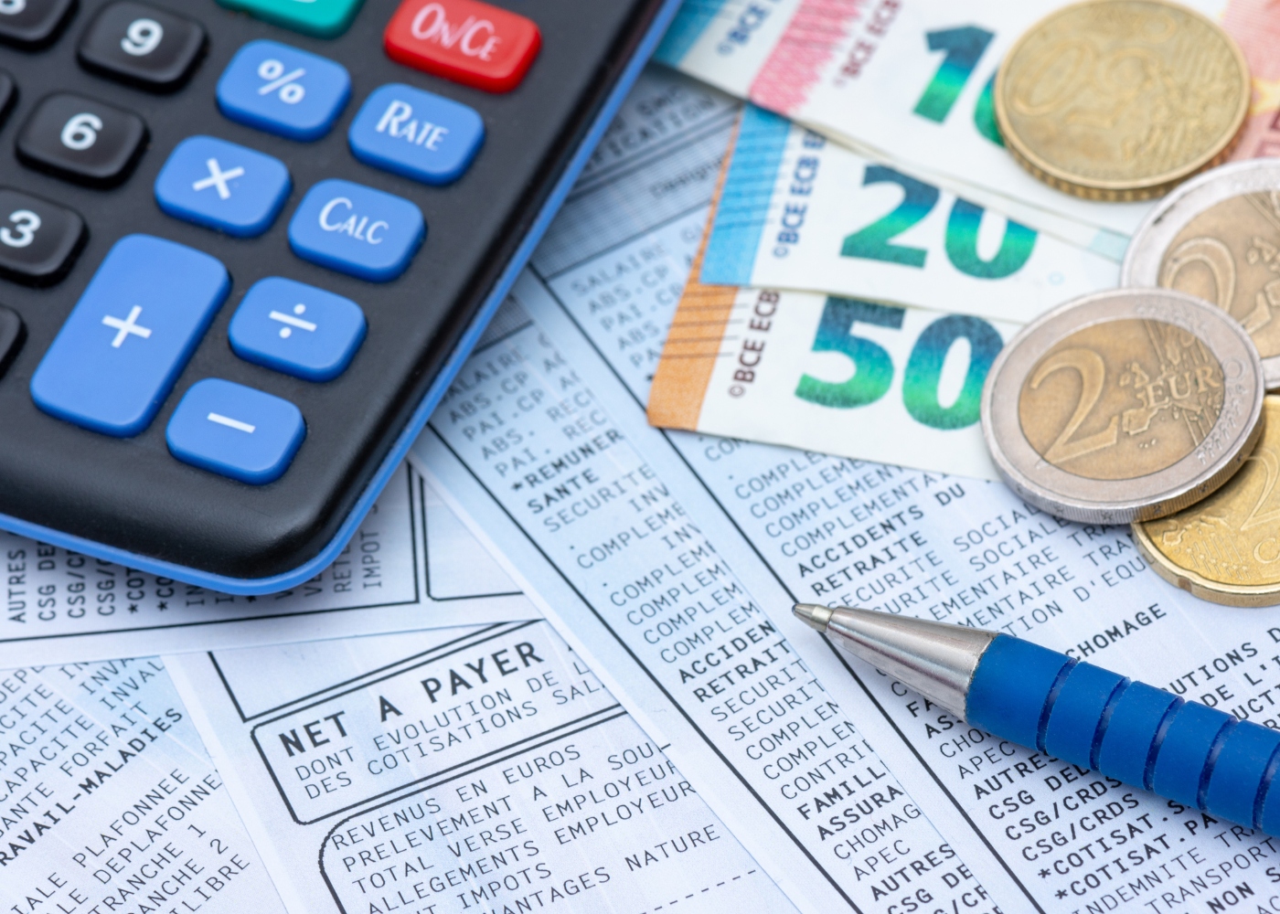 calculadora, dinheiro, papéis e caneta disposto em cima de mesa