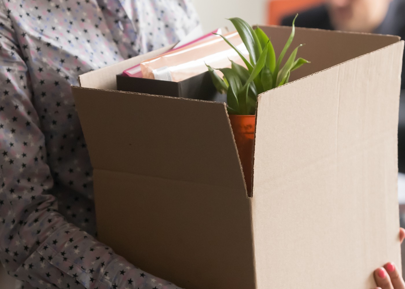 pessoa a segurar uma caixa com os seus pertences do escritório e a pensar no despedimento: tempo a dar à empresa
