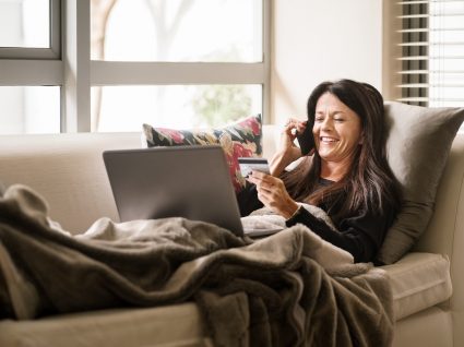 mulher a fazer pagamentos online no computador deitada no sofá