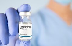 Profissional de saúde a mostrar frasco de vacina contra a COVID-19